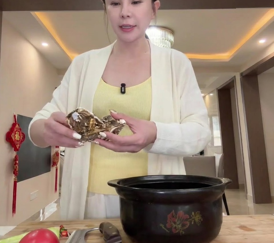 커다란 검은색 뚝배기 바닥에 담기고 있는 생굴의 모습.