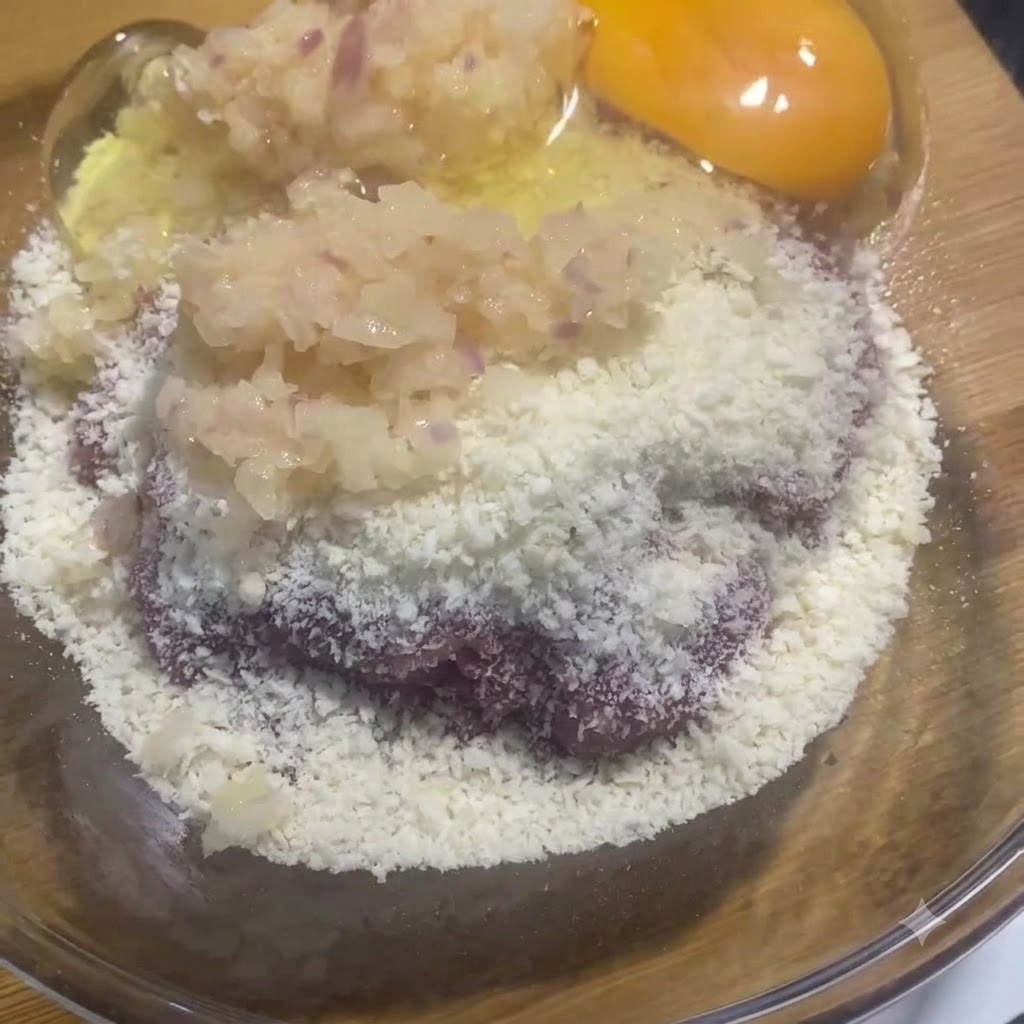 고기 및 양파 혼합물 옆 유리 볼에 신선한 달걀 노른자와 흰자가 담겨 있는 모습.