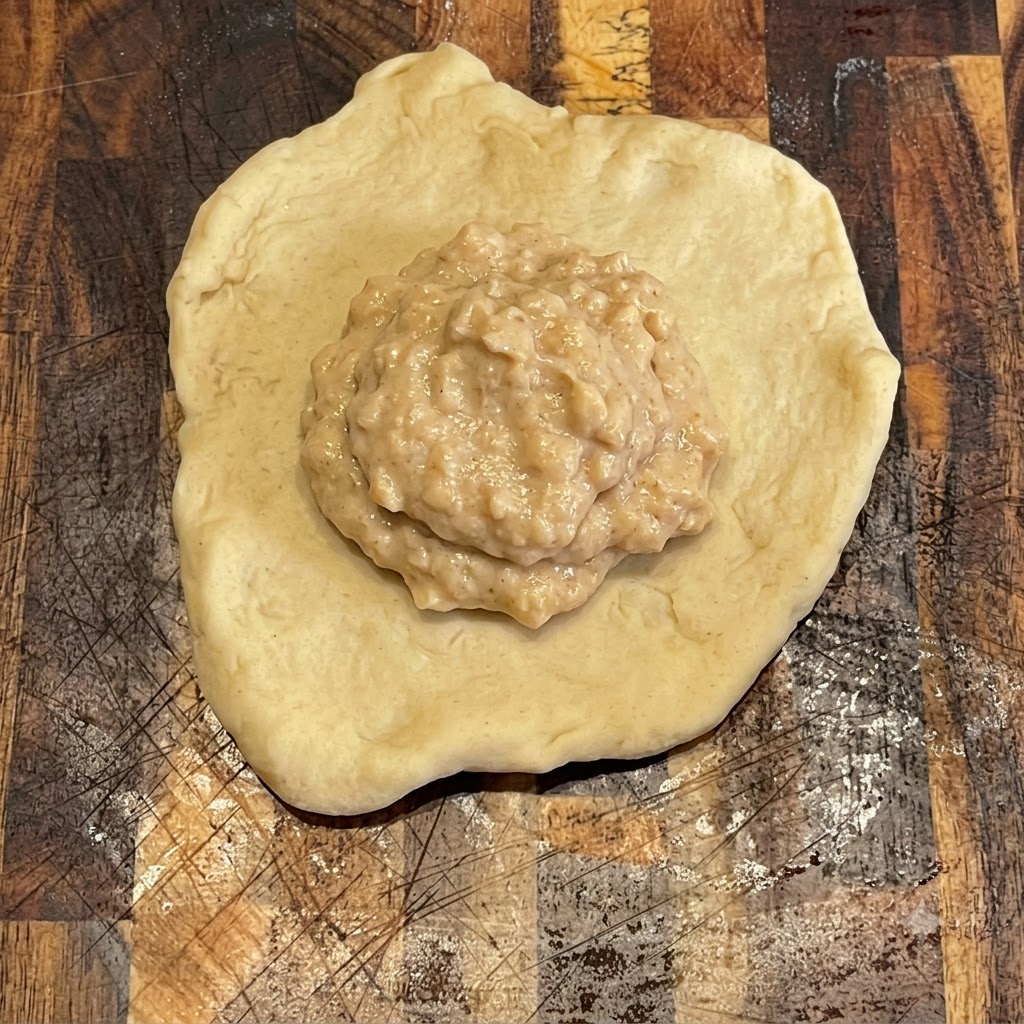 나무 도마 위의 납작하고 둥근 반죽 위에 깔끔하게 발려진 버거 소스.