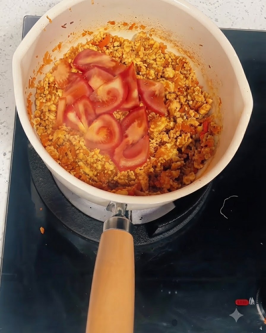 물과 토마토 페이스트가 추가되는 조리된 재료가 담긴 냄비 속 토마토 슬라이스.