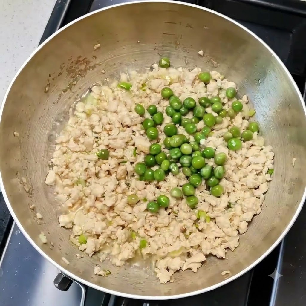 요리 팬 안에서 닭고기 및 향신 채소와 완두콩이 고르게 섞여 있는 모습.