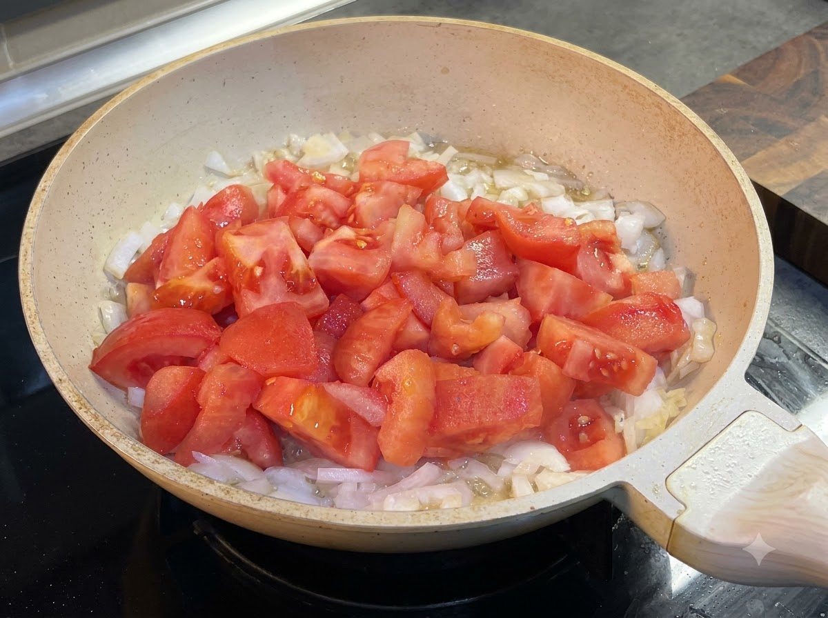 토마토와 양파가 있는 팬에 케첩을 짜 넣는 모습.