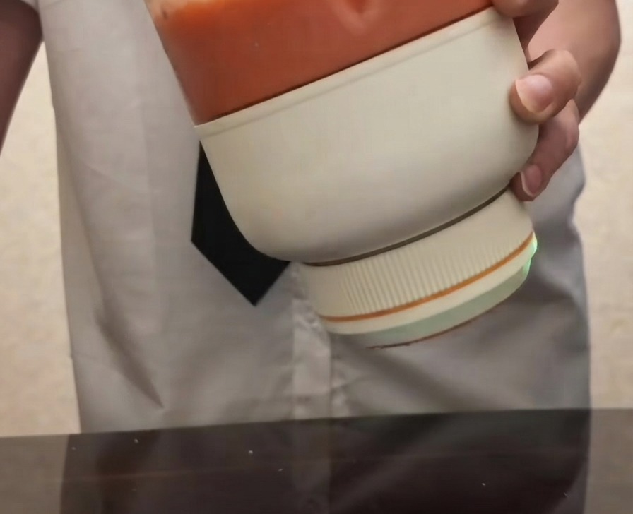 부드럽고 밝은 붉은색의 토마토 퓌레가 담긴 휴대용 전동 블렌더를 들고 있는 모습.