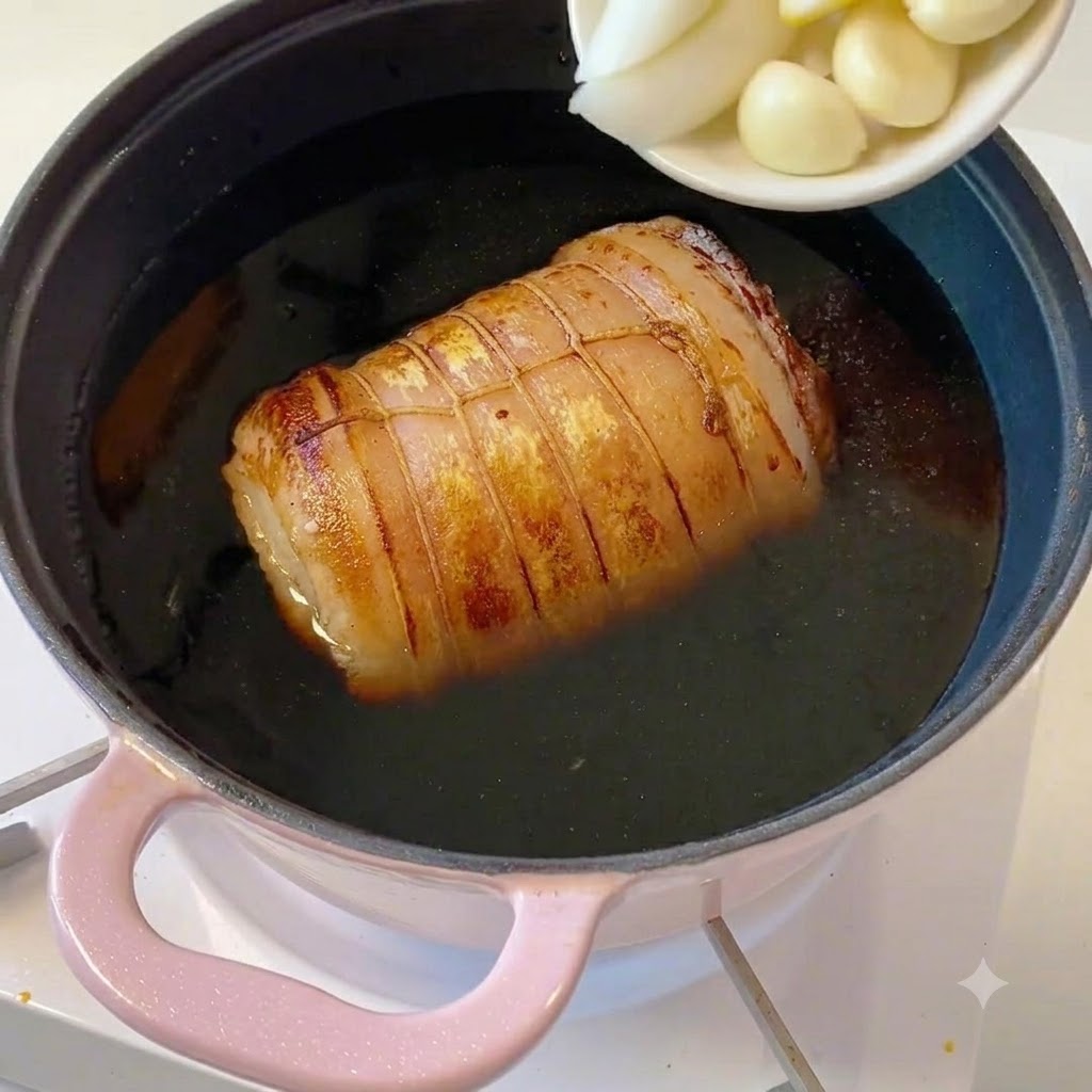 썰어둔 파, 생강 조각, 통마늘이 담긴 작은 흰색 그릇을 냄비에 털어 넣는 모습.