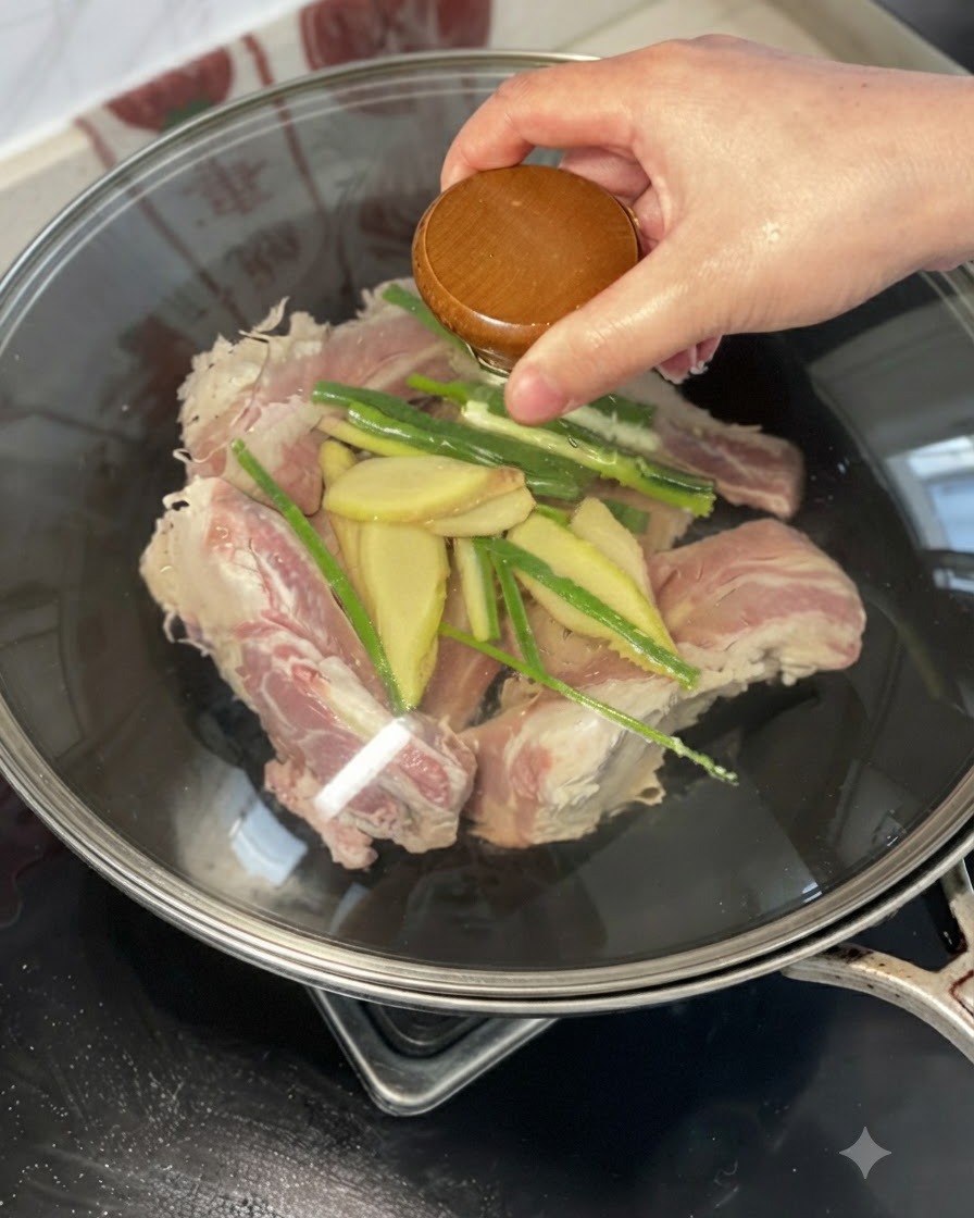 웍에 담긴 소갈비, 생강, 대파 위에 황주를 붓는 모습.