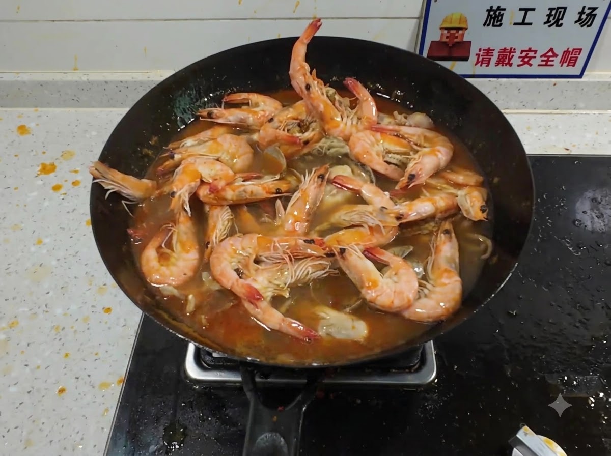 해산물과 진한 붉은 육수가 끓고 있는 웍에 큰 랍스터를 추가하는 모습.