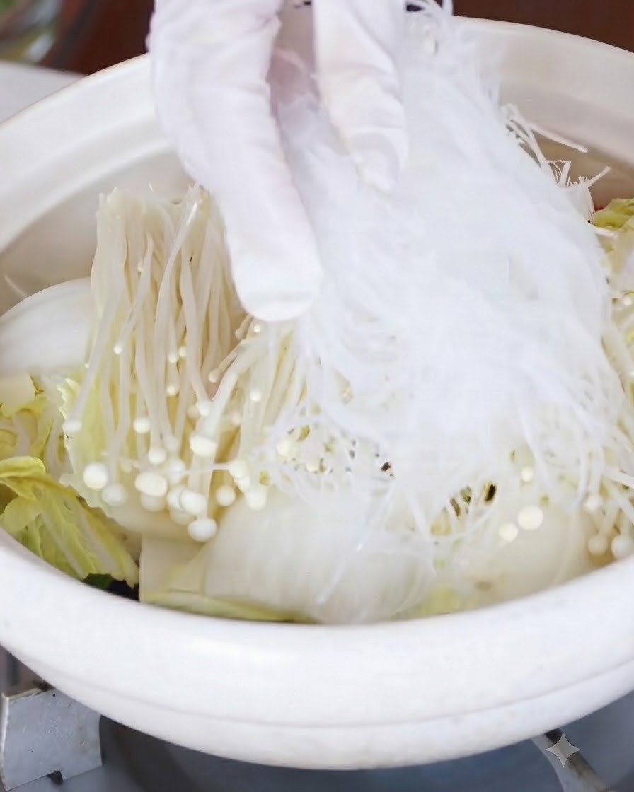 팽이버섯과 배추 층 위에 불린 당면을 올리고 있는 모습.