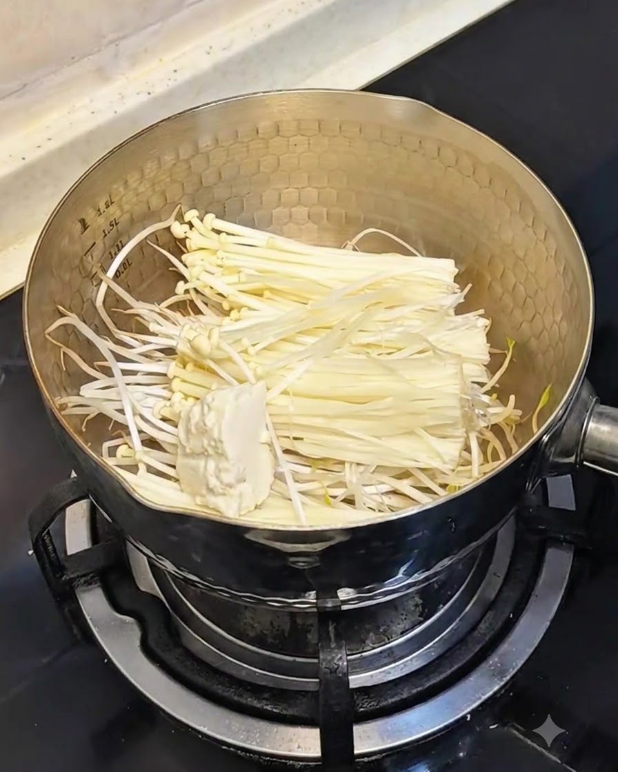 버섯과 콩나물이 담긴 냄비에 숟가락으로 부드러운 연두부를 덜어 넣는 모습.