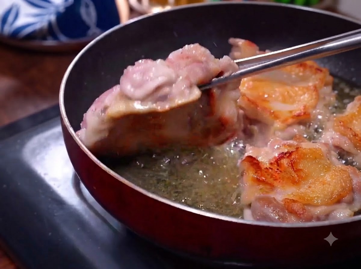 팬에서 노릇노릇해진 닭 껍질이 보이도록 집게로 닭고기를 뒤집는 모습