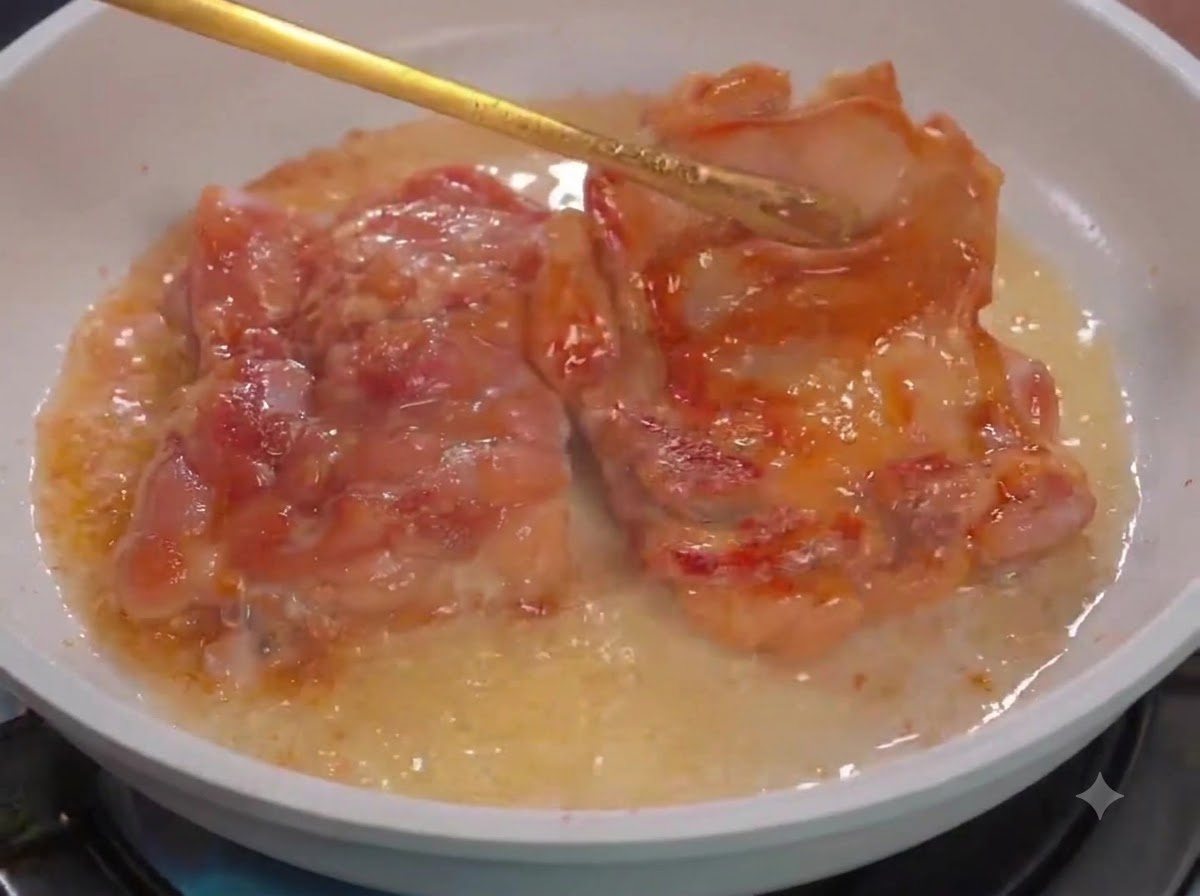 하얀 팬 안에서 집게로 오일과 함께 닭고기 조각들을 뒤집는 모습.