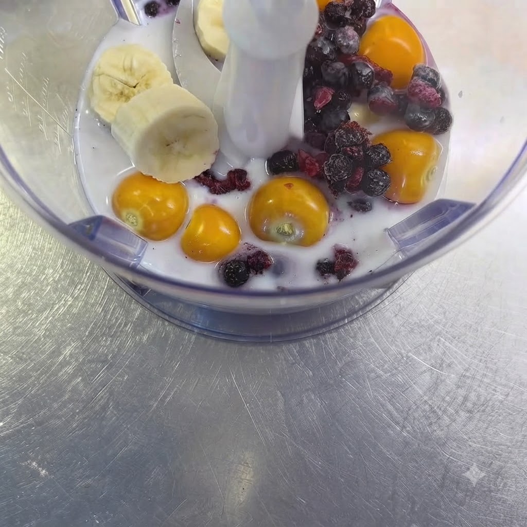 믹서기 컵 안의 과일과 우유 혼합물 사이에 놓인 생마늘 한 쪽.