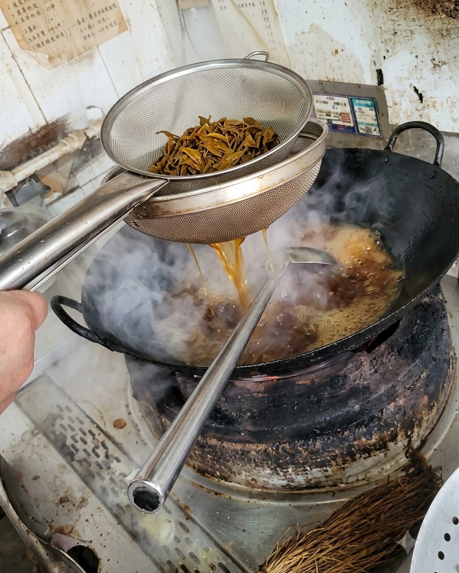 금속 체에 담긴 데친 버섯에서 물기가 빠져나가고 아래쪽 웍으로 떨어지는 모습.