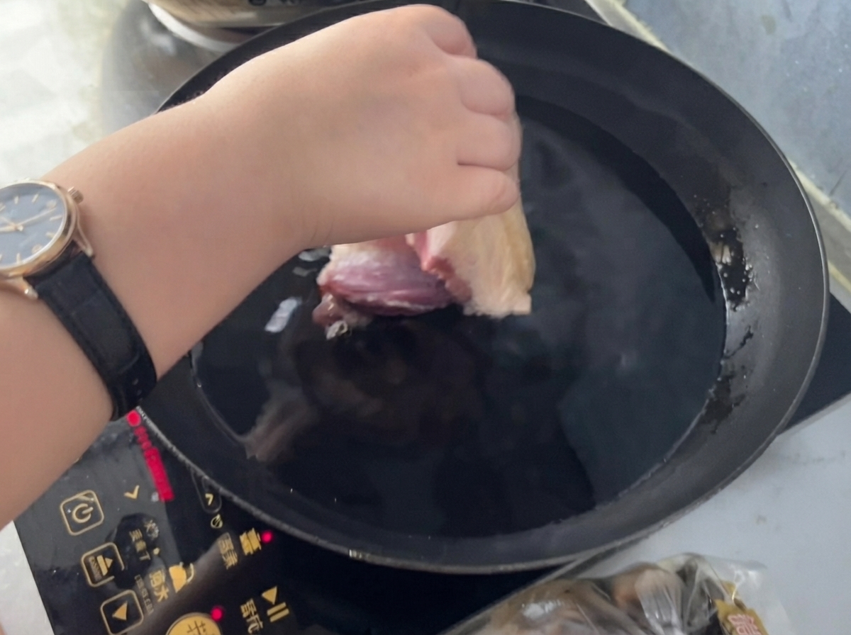 생강과 요리술이 담긴 찬물 냄비에 돼지고기를 넣고 있는 손.