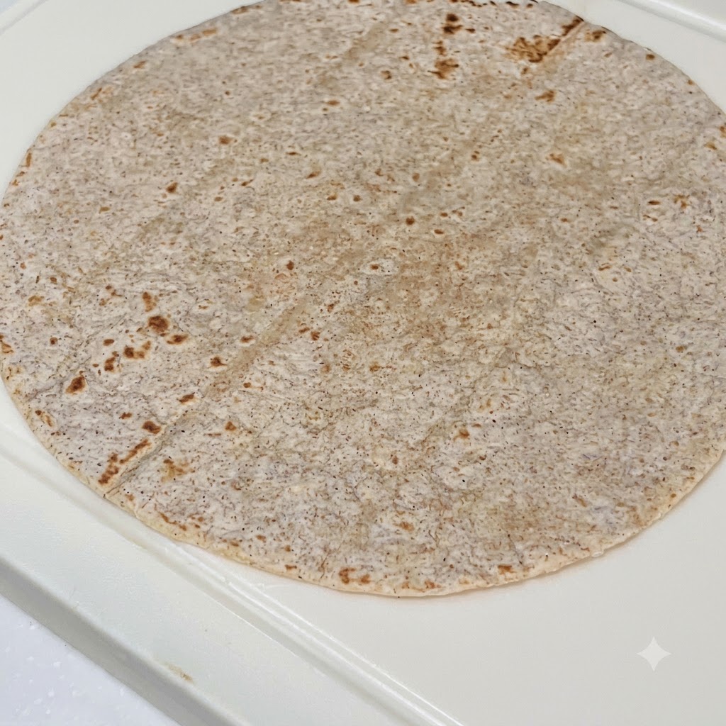 통밀 토르티야 위에 피넛버터 소스, 썰어둔 닭가슴살, 적채, 신선한 상추가 차례로 얹어진 모습