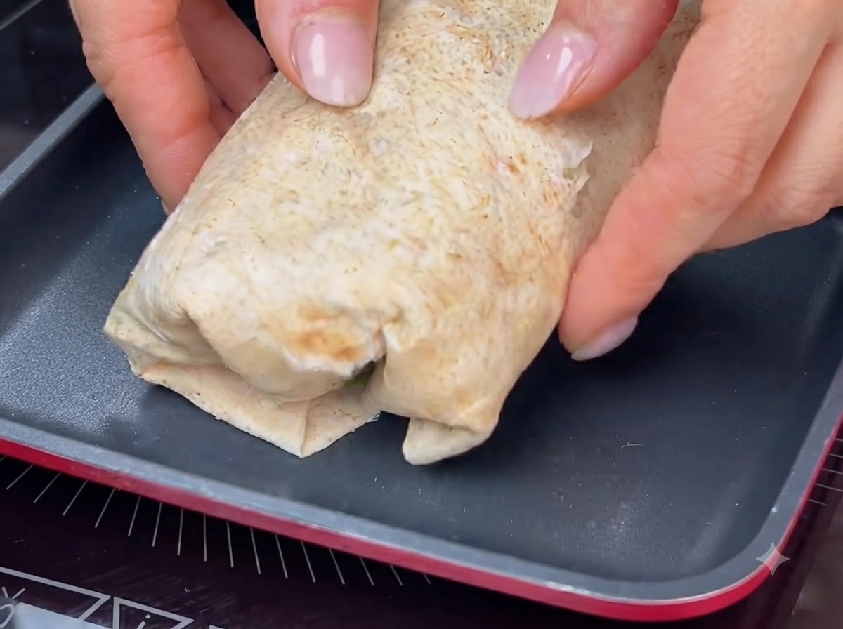 잘 말아진 랩을 뜨거운 팬에 올려 겉면을 노릇하고 바삭하게 토스트하는 모습