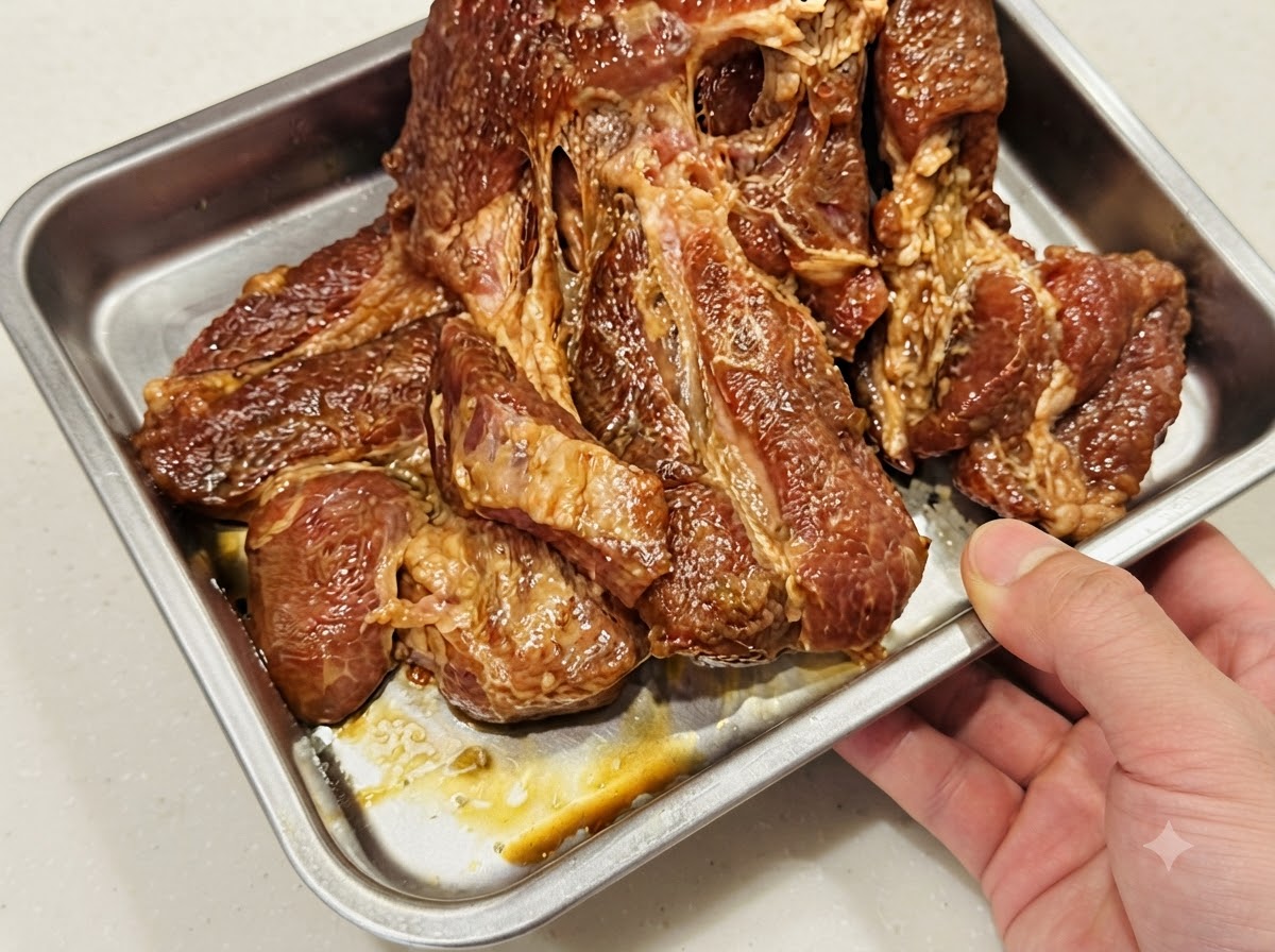 은박 호일이 깔린 금속 베이킹 트레이에 한 겹으로 평평하게 놓인 돼지고기.