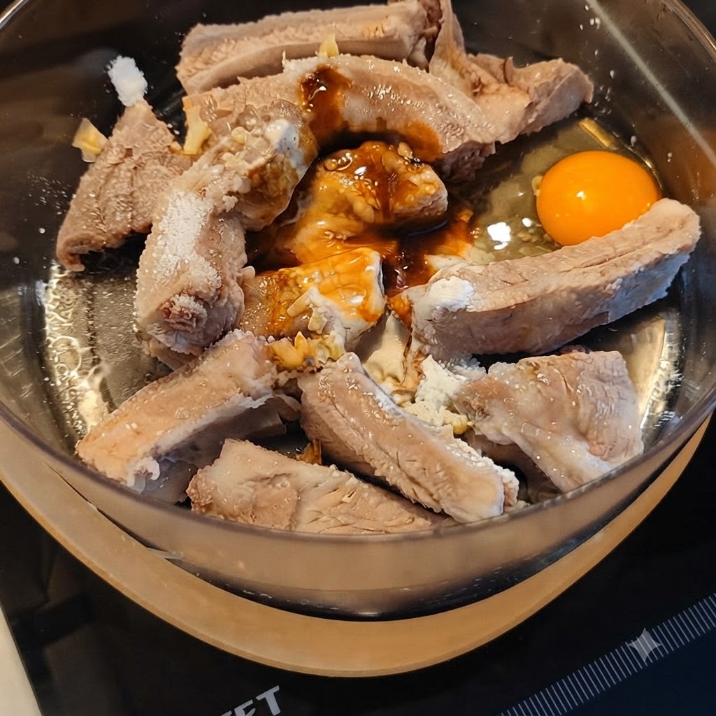 다양한 소스와 깬 달걀이 들어간 믹싱볼에서 돼지갈비를 버무리는 모습.