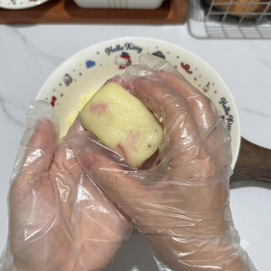장갑을 낀 두 손으로 감자 반죽 조각을 깔끔한 직사각형 패티 모양으로 빚는 모습.