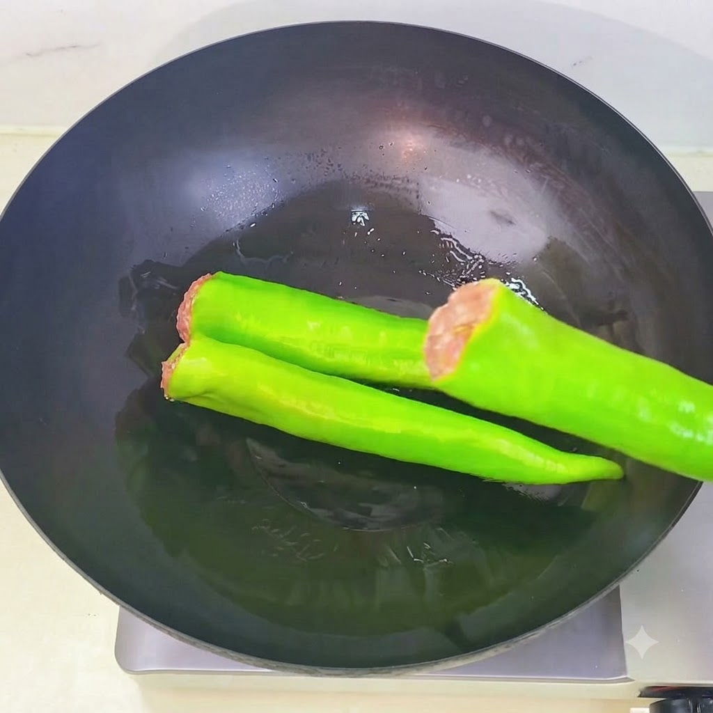 속이 채워진 꽈리고추들이 기름이 둘러진 예열된 웍 안에 차례대로 나란히 배열되어 있는 모습.