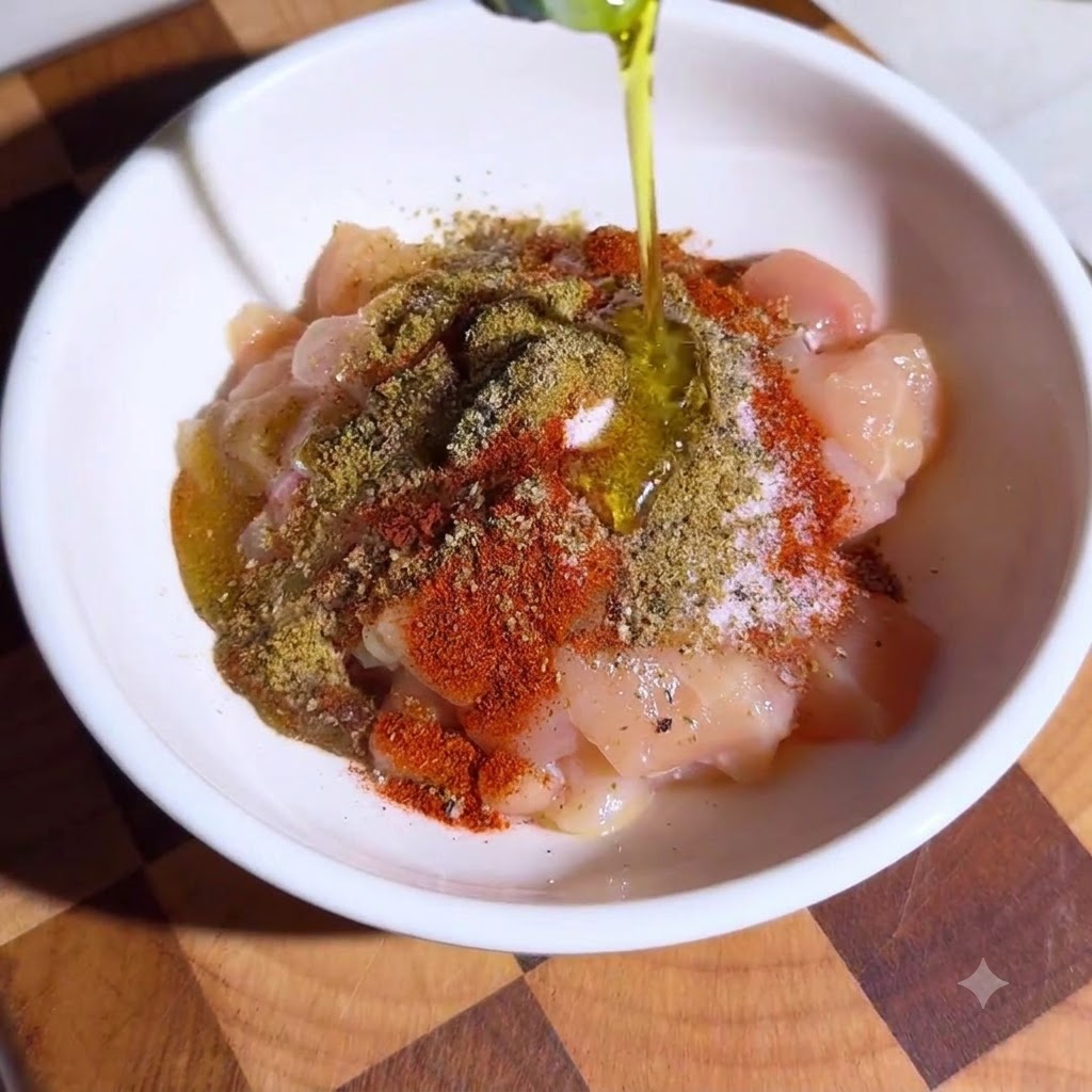 혼합된 향신료와 올리브 오일로 듬뿍 시즈닝된 깍둑썰기한 닭고기로 채워진 그릇.