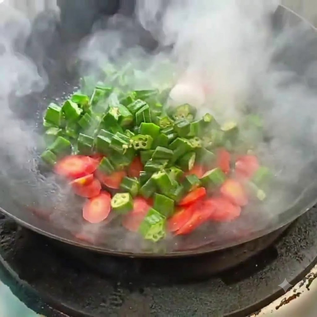 김이 모락모락 피어오르는 뜨거운 웍에서 썰어둔 오크라와 당근을 볶는 모습.