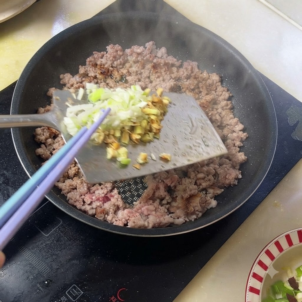 팬에서 조리 중인 다진 돼지고기에 다진 대파와 생강을 넣는 모습.