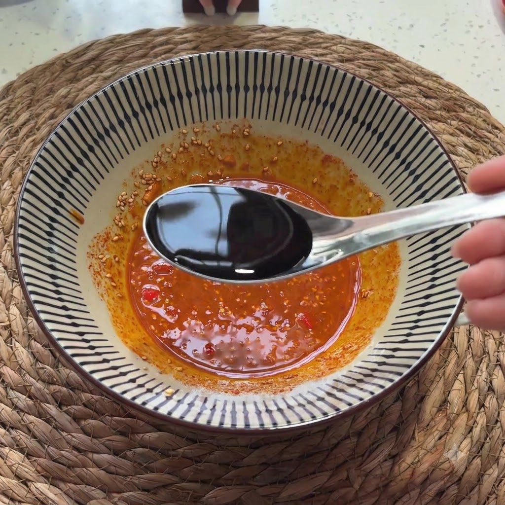 숟가락에서 양념 소스 혼합물로 진간장이 부어지는 모습.