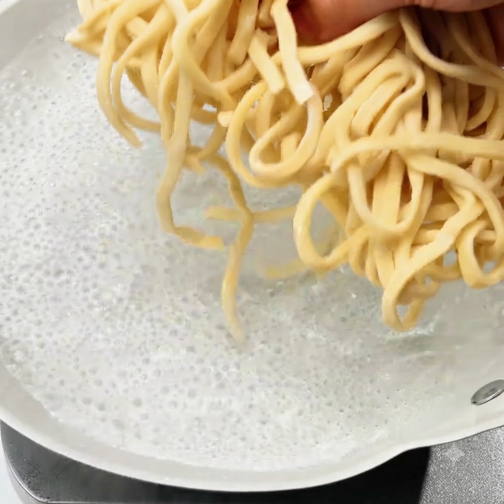 끓는 물이 담긴 냄비에 생면을 넣는 모습.