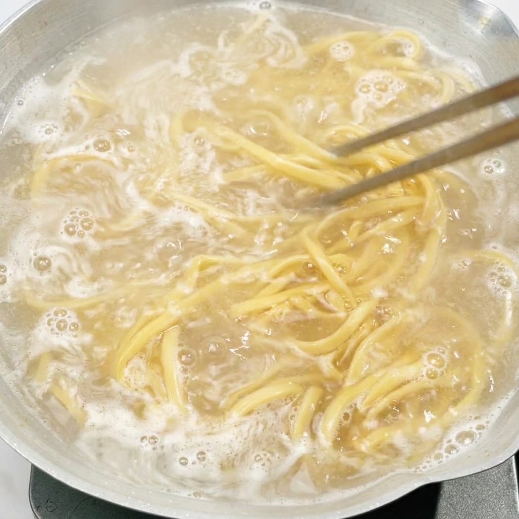 냄비에 끓고 있는 면을 젓가락으로 젓고 있는 모습.