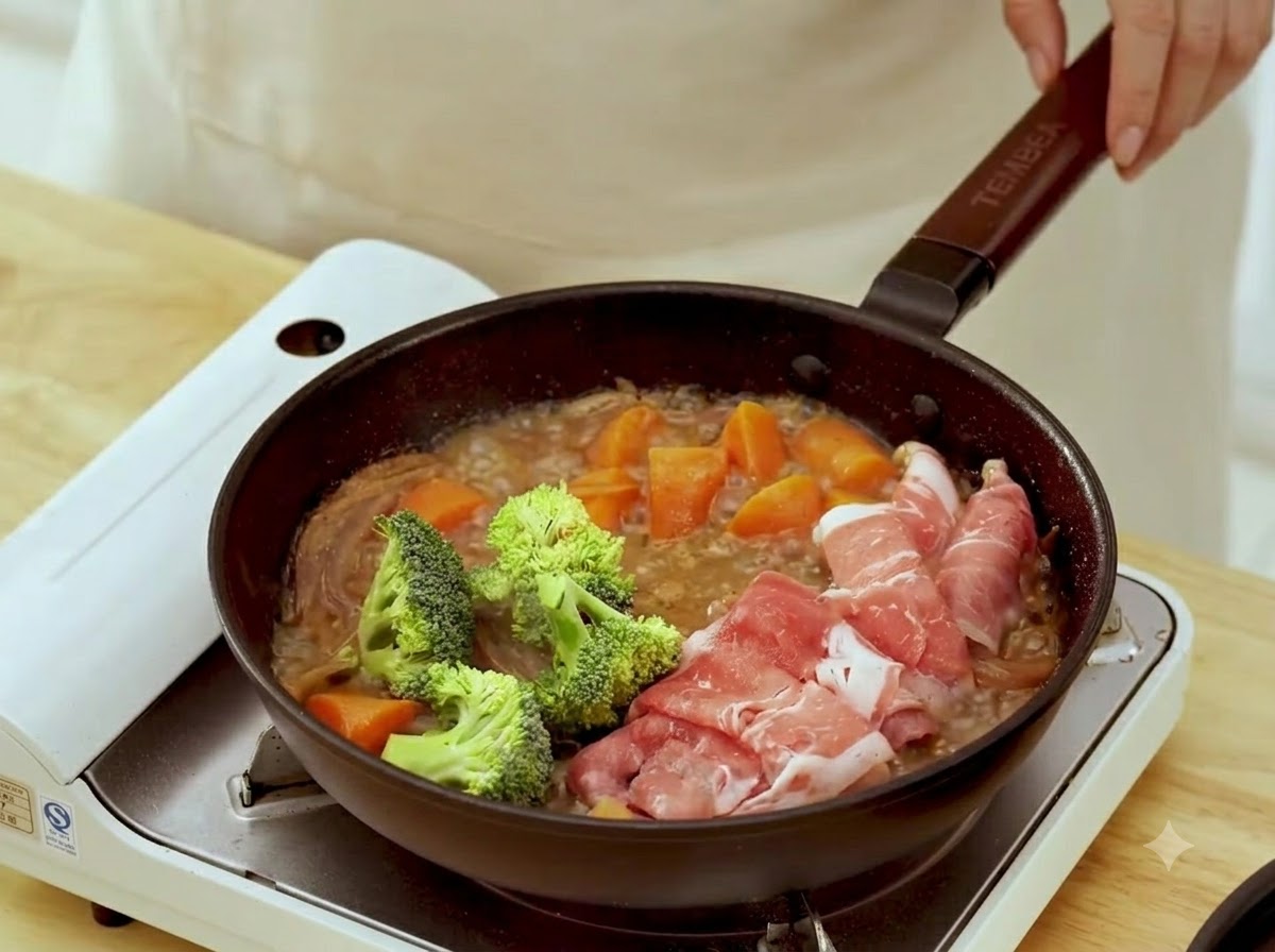 조리 중인 소고기 말이 옆 끓는 팬에 신선한 녹색 브로콜리 송이를 넣고 있는 모습.