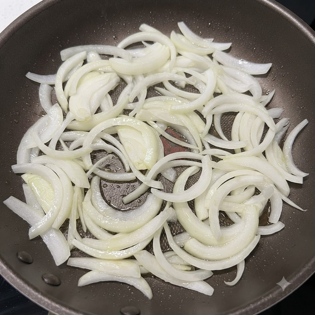 달궈진 팬에 채 썬 양파를 넣고 가장자리가 노릇해질 때까지 볶는 모습.
