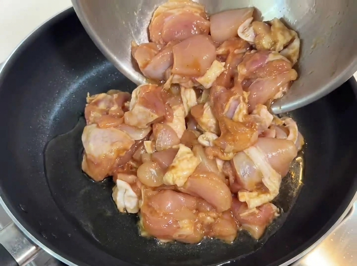 달궈진 기름을 두른 팬에 양념된 닭고기를 넣는 모습.
