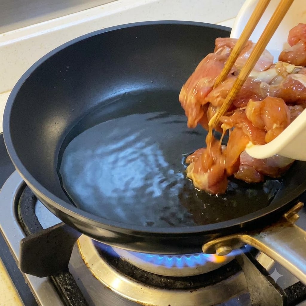 달궈진 식용유 팬에 젓가락으로 밑간된 닭고기를 넣는 모습.