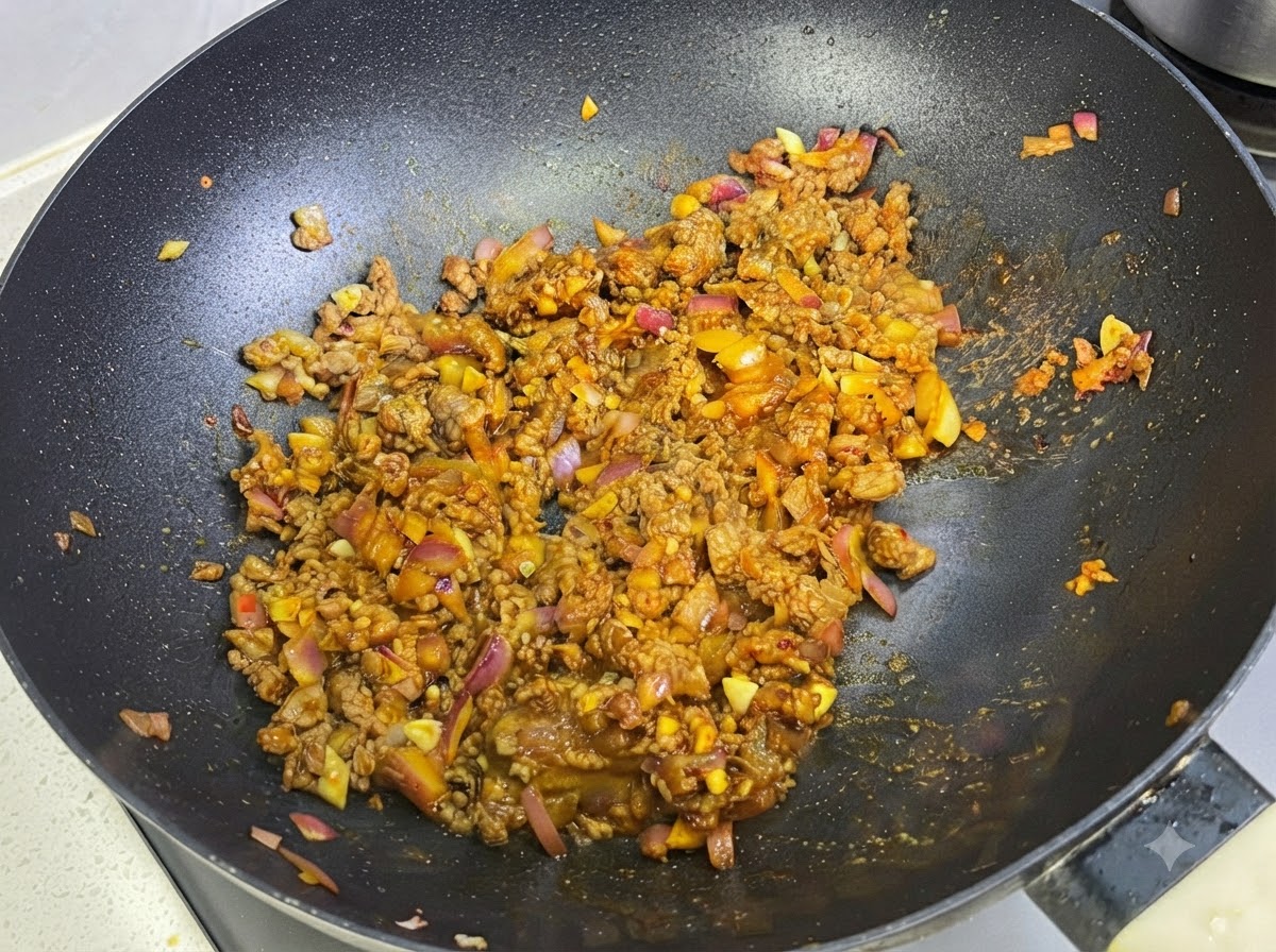 팬 안의 카레 고기 소스에 우유를 섞는 모습.