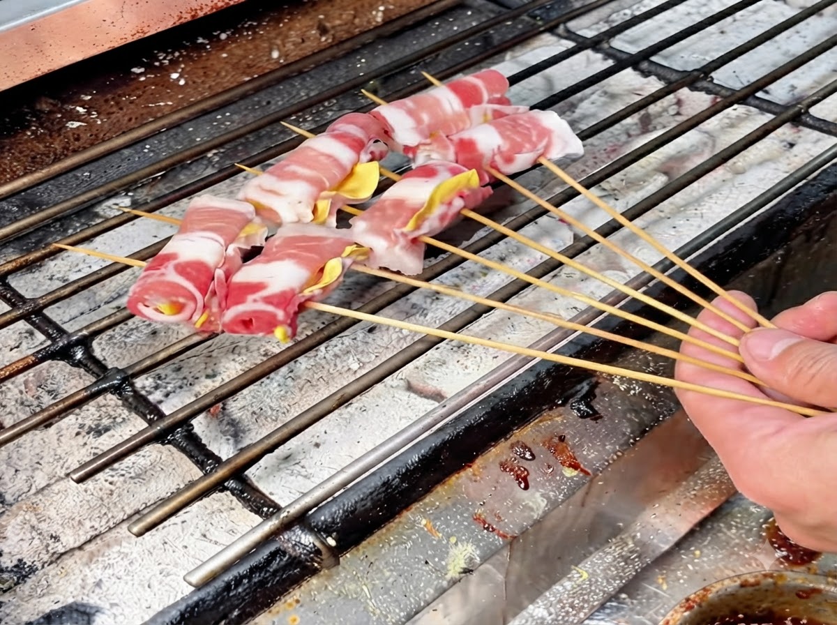 천천히 굽기 위해 뜨거운 숯불 그릴 그레이트 위에 배열된 여러 개의 꼬치 고기 롤.