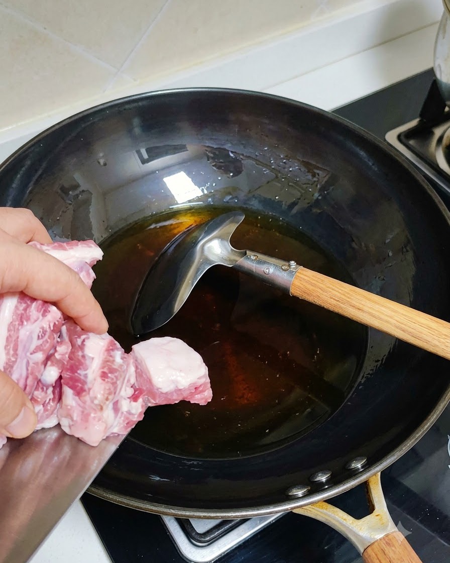 기름이 둘러진 달궈진 웍에 데친 돼지고기 갈비를 넣고 있는 모습.