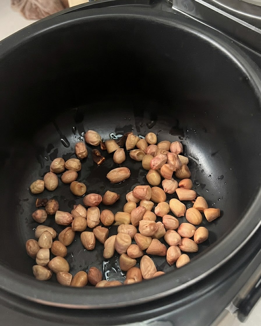 검은색 전기 찜기 바닥에 흩어져 있는 미리 불린 땅콩.