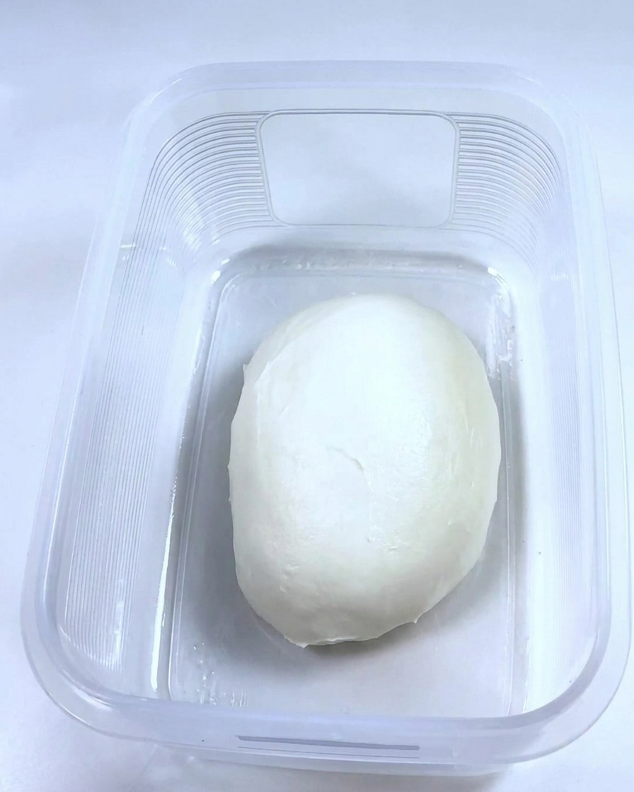 오일을 바른 깨끗한 직사각형 플라스틱 용기 안에 부드러운 반죽 덩어리가 들어 있는 모습