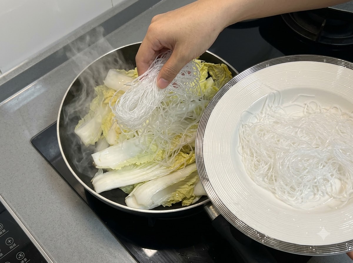 팬 안의 배추 층 위에 당면을 올려놓는 모습.