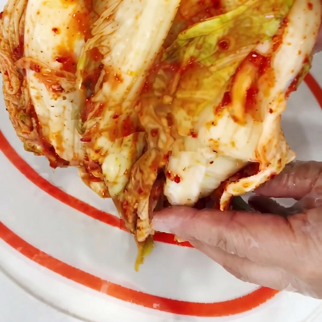 도마 위에서 김치 반 포기를 먹기 좋은 크기로 썰고 있는 모습