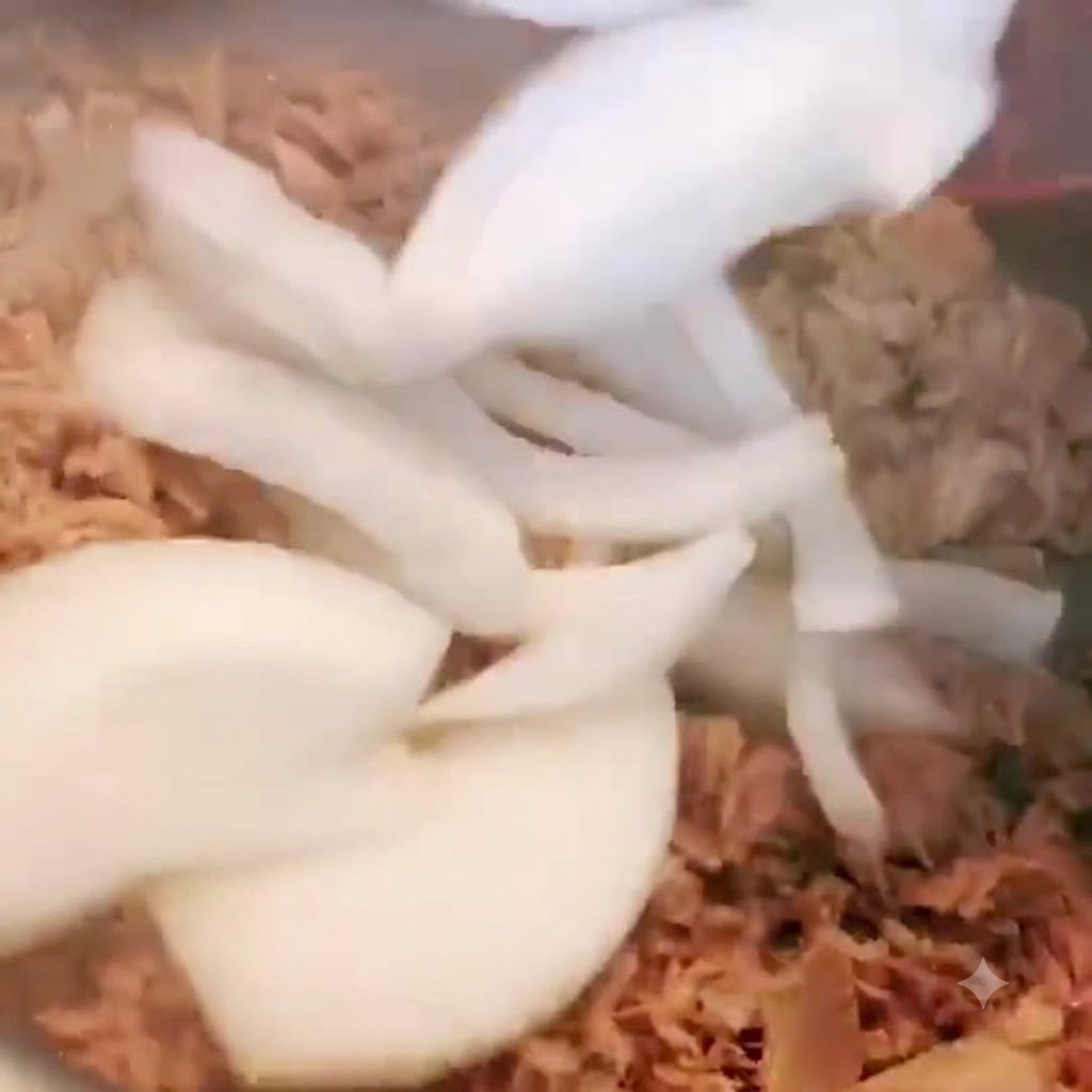 참치가 담긴 냄비에 채 썬 양파를 넣고 함께 섞으며 볶는 모습