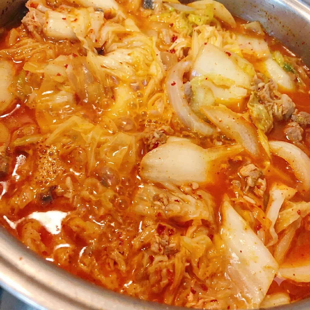 끓고 있는 김치 참치찌개에 고춧가루를 넣고 있는 모습