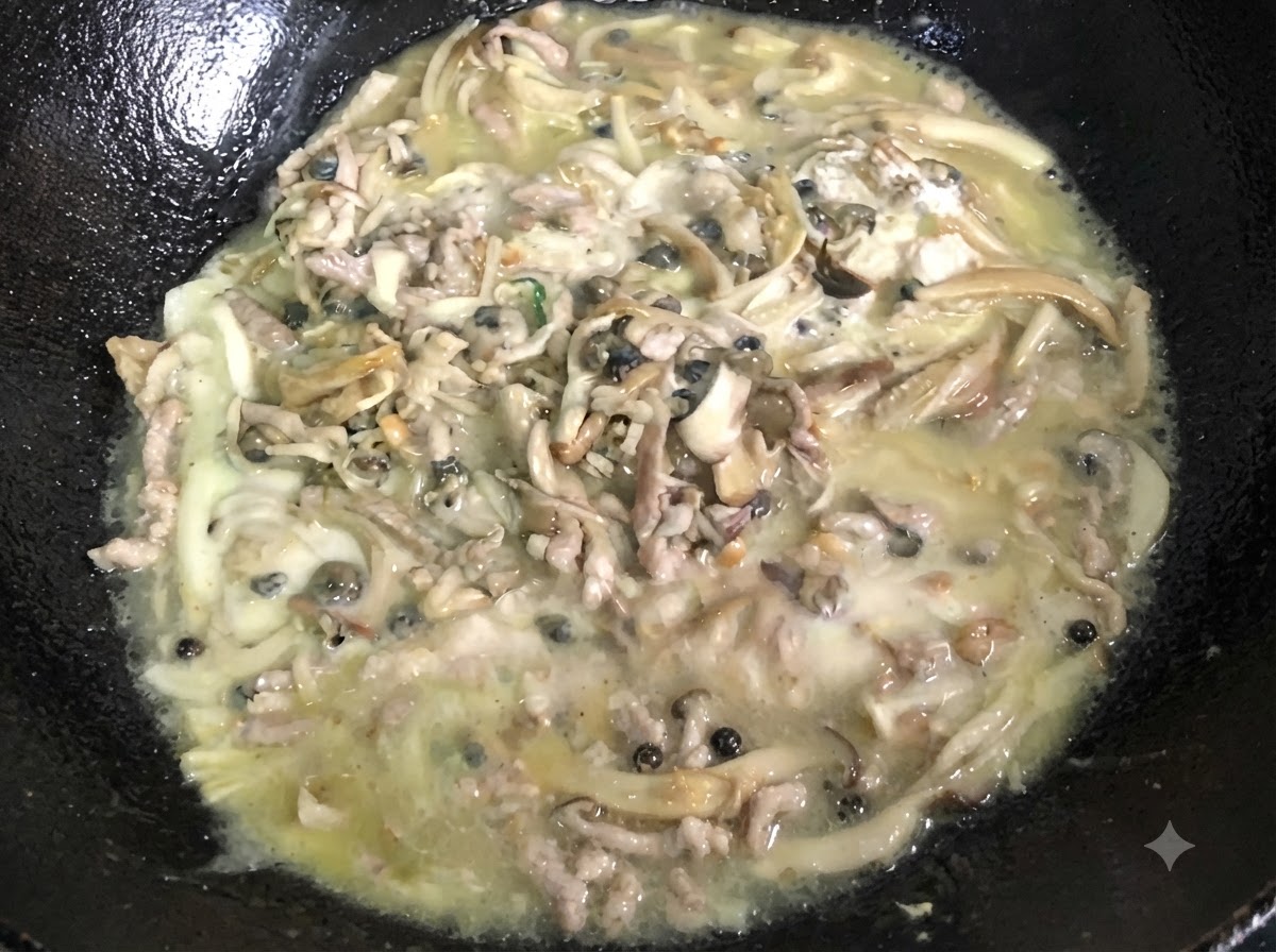 검은색 웍 안에서 걸쭉하고 보글보글 끓는 혼합물을 계속해서 저어주고 있습니다.