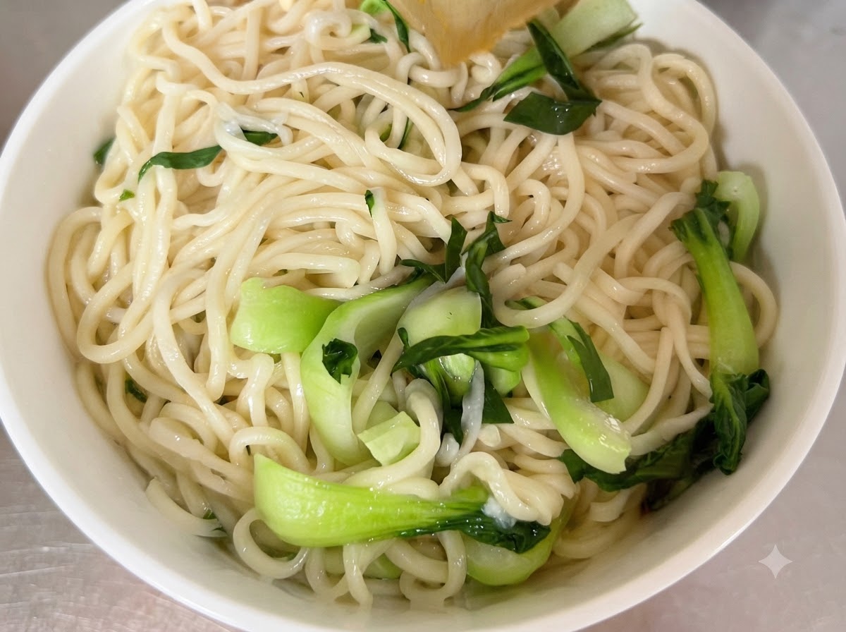 하얀 서빙 그릇에 삶아진 면과 신선한 청경채가 담겨 있는 모습.