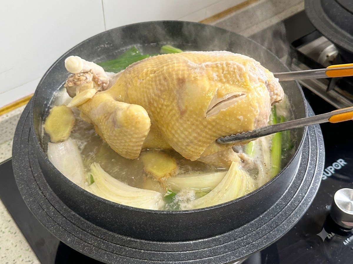 끓는 육수 안에서 조리용 집게로 통닭을 뒤집는 모습
