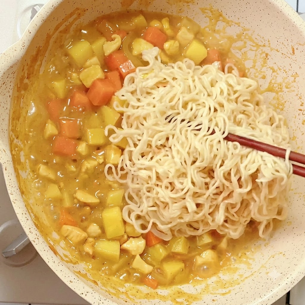 걸쭉해진 카레 소스에 젓가락으로 미리 삶아둔 인스턴트 라면을 넣는 모습