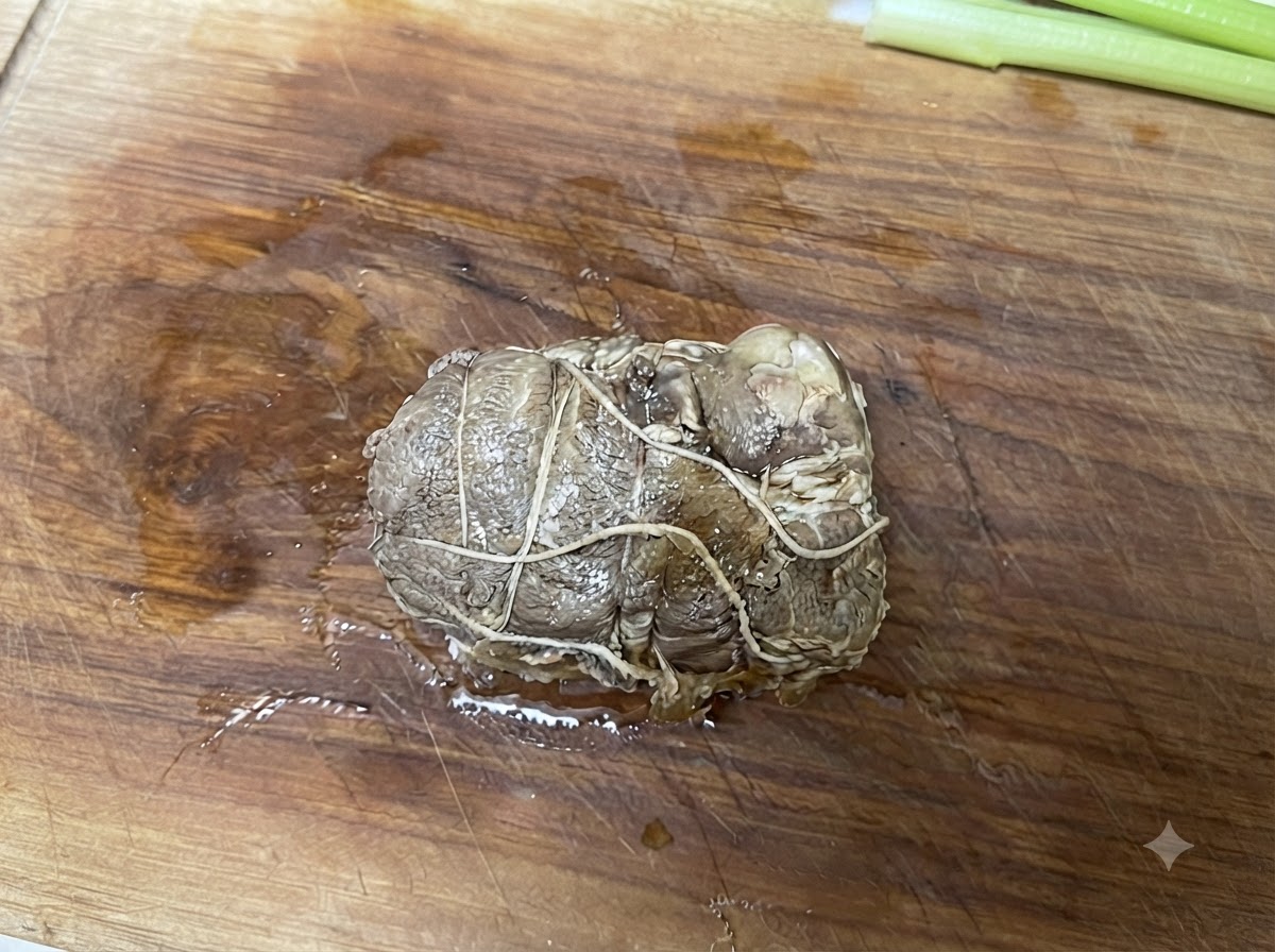 나무 도마 위에 올려진 끈으로 묶인 롤 형태의 돼지고기 차슈.