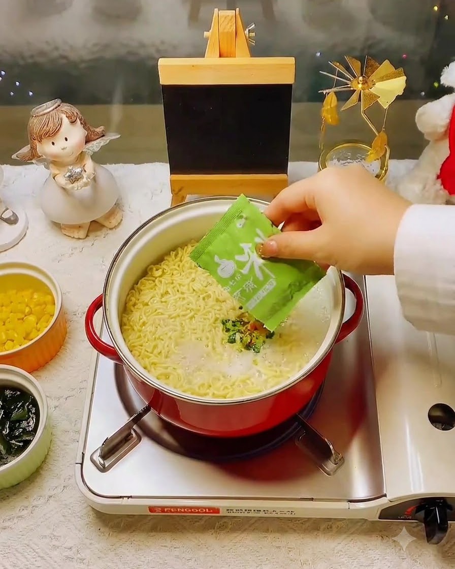 면과 육수가 담긴 냄비에 초록색 건더기 수프를 넣는 손.