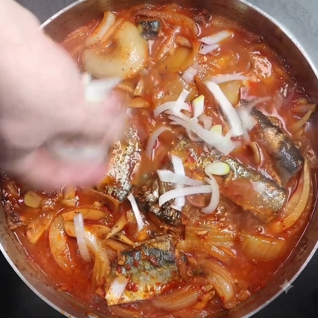 생선 조림 위에 썬 대파를 뿌리는 모습.