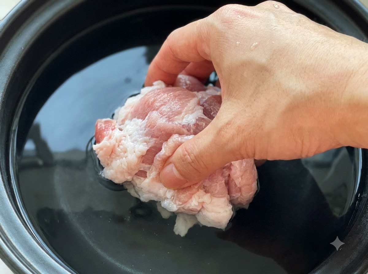 차가운 물과 된장이 담긴 냄비에 생고기 조각을 넣는 모습.